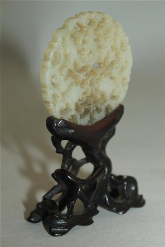 A Chinese celadon jade plaque, 18th / 19th century, 5.3cm, glued to a rosewood stand, overall height 9.5cm